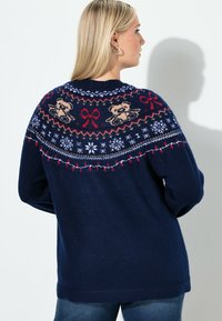 Granatowy sweter z dzianiny z kolorowym wzorem na karczku, przedstawiającym misie, kokardy, płatki śniegu oraz dekoracyjne akcenty wzdłuż dekoltu.