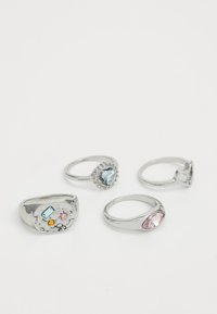 Cuatro anillos de plata con diversas piedras preciosas: uno tiene una piedra de color azul claro en forma de corazón, otro presenta un diseño adornado, y los demás tienen diferentes formas y colores.