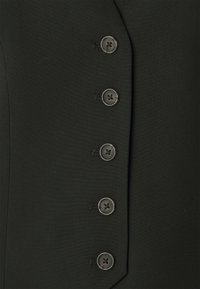 Svart tyg med en slät textur som har fem mörka knappar fram, vilket framhäver en skräddarsydd design och sömnadsdetaljer.