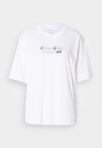 Witte katoenen t-shirt met een ronde halslijn en korte mouwen. Bevat grijze tekst "Calvin Klein Since 1968" centraal aan de voorkant.