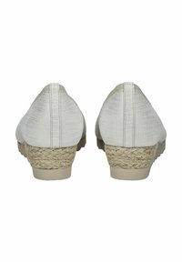 Zapatos de tacón de tela blanca con acabado texturizado. Presentan un tacón de cuña envuelto en yute y una base suave y sólida. Vista trasera que muestra la altura del tacón.