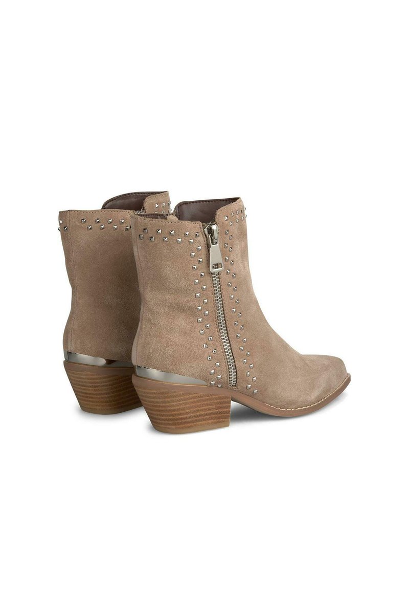 Botines de ante beige con tachuelas plateadas, cremallera lateral y tacón marrón en bloque. Presentan una puntera afilada y suela plana.