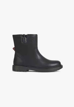 Bota de tornozelo em couro preto com fecho lateral, bico redondo e pequeno salto bloco. Apresenta uma faixa decorativa com fivela e painéis texturizados.