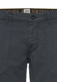 Graue Stoffhosen mit geripptem Muster, Knopfverschluss und seitlichen Taschen. Der innere Bund hat ein kontrastierendes Logomuster.