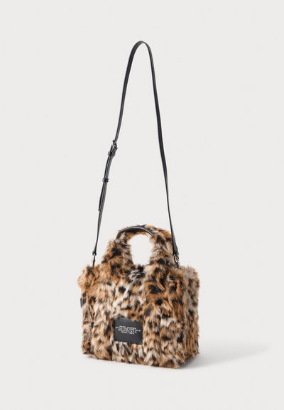Petit sac à main rectangulaire avec imprimé léopard en fausse fourrure et bandoulière noire réglable suspendu sur fond blanc.