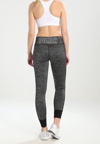 Czarno-szare legginsy w wzór, z tapered fit i czarnymi mankietami, z wyraźnym szarym logo na pasku.