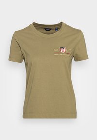 Olijf groene katoenen T-shirt met korte mouwen, een ronde hals en een geborduurd logo met rode en witte strepen op de linkerkant van de borst.