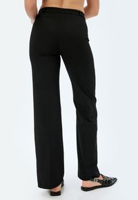 Zwarte, hoge taille wijdvertrokken broek gemaakt van rekbare stof, met een soepele textuur en zonder zichtbare patronen of versieringen.