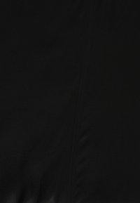 Musta kangas, jossa on sileä tekstuuri ja sauman yksityiskohta. Materiaali vaikuttaa pehmeältä ja hieman joustavalta.