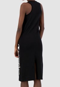 Czarna sukienka z bawełny na ramiączkach z rozcięciem po bokach i białym detalem z logo "Champion". Prosty, dopasowany krój z okrągłym dekoltem i bez rękawów.