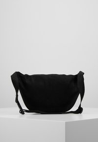 Borsa in tessuto nero con una superficie liscia, forma arrotondata e tracolla regolabile. Presenta un design minimalista senza hardware o accenti aggiuntivi.