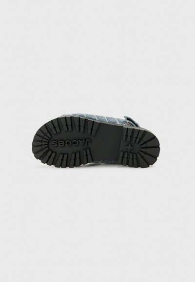 Denim schoenen met een gestructureerde bovenkant en een zwarte rubberen zool. Heeft een patroon op de loopzool voor grip en een gesp voor een veilige sluiting.