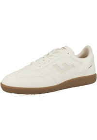 Vit lädersportssko med en texturerad gummisula, som har en framträdande logotyp och snörning. Slät ovansida.