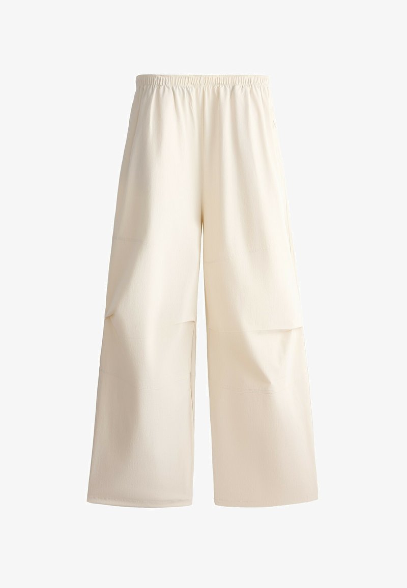 Pantalon ample couleur crème avec taille élastique et poches plaquées à l’avant, en tissu doux.