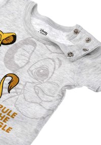 Grijze katoenen shirt met korte mouwen, featuring dierengraphics en de tekst "Heers over de Jungle", met drukknoopjes op de schouder voor gemakkelijk aankleden.