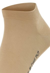 Calzino beige alla caviglia realizzato in materiale morbido ed elastico con una fascia a coste. Presenta una scritta stampata sul lato con la dicitura "Cool 24/7."