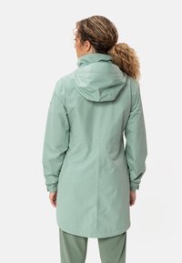 Giacca impermeabile verde menta con cappuccio, polsini arricciati e silhouette di lunghezza media. Texture liscia e design minimalista.