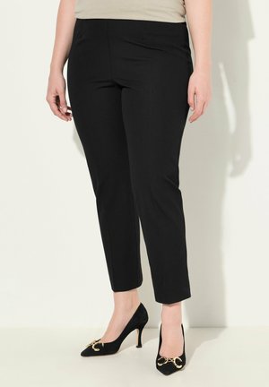 Pantaloni neri su misura con un design a gamba dritta e una texture liscia. Abbinati a tacchi alti neri con un dettaglio in oro.