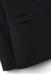 Primer plano de una tela negra con dos bolsillos de ojal horizontales que presentan un detalle de doble ribete en una prenda.