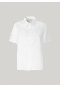 Chemise blanche à manches courtes avec broderie œillet florale subtile et col pointu sur fond neutre.