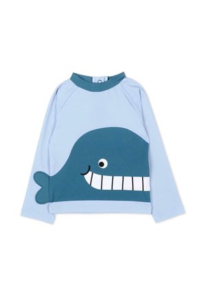 Jasnoniebieska koszula z długim rękawem z grafiką uśmiechniętego ciemnoniebieskiego wieloryba, z naszytym ogonem po jednej stronie i wysokim kołnierzem.