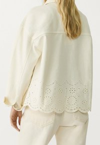 Denimjack in roomkleur met een scalloped kanten zoom met oogjes en bloemenperforaties, voorzien van lange mouwen en een kraag.
