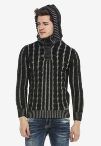 Schwarzer und grauer Strickpullover mit Kapuze, ausgestattet mit einem strukturierten Rippenmuster und Knopfakzenten. Lange Ärmel und taillierte Passform.
