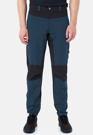 Herren Outdoorhose in Blau und Schwarz mit verstärkten Knien und schwarzen Schnürschuhen, dargestellt von der Taille bis zu den Füßen.