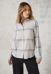 Camicia a maniche lunghe con bottoni di colore grigio chiaro con motivo a quadri blu e lavanda. Presenta un colletto classico e polsini con bottoni. Tessuto dalla consistenza liscia.