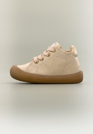 Μπεζ υφασμάτινο sneaker ψηλής κορυφής με ανοιχτό ροζ κορδόνια και παχιά καφέ λαστιχένια σόλα σε απλό ουδέτερο φόντο.
