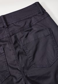Pantalons bleu marine foncé avec une texture lisse, présentant un design simple, une poche arrière et une couture précise le long de la taille et des coutures.