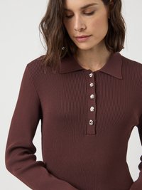 Haut marron à côtes, à boutons, avec un col, présentant des boutons en argent et des manches longues. La texture est lisse avec un design ajusté.
