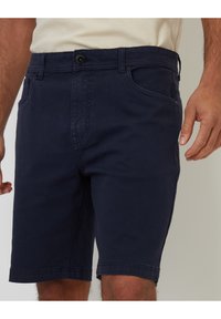 Pantalones cortos de algodón azul marino con cierre de botón, bolsillos laterales y dobladillos cosidos. La tela tiene una textura suave y un ajuste casual.