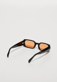 Gafas de sol rectangulares negras con lentes naranjas, con un marco grueso y brazos estilizados, acabado pulido y sutiles acentos metálicos.