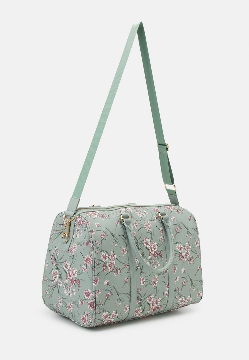 Sac de voyage floral en vert menthe, fabriqué à partir d'un matériau texturé. Présente un motif floral rose, des poignées doubles et une bandoulière réglable.