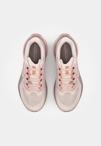 Zapatillas de running Nike con un upper de malla en rosa claro, acentos en oro rosa, seis ojetes y una suela texturizada.