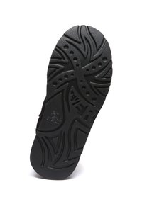 Black rubber shoe sole featuring a textured zigzag pattern and circular cutouts, with the brand name embossed on the surface.