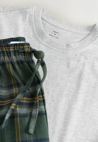Sivá bavlnená tričko s okrúhlym výstrihom vedľa zelených károvaných pyžamových nohavíc s žltými a modrými pruhmi a s opaskom na sťahovanie.