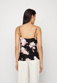Débardeur noir à motif floral avec des fleurs roses et blanches, bretelles spaghetti ajustables et coupe décontractée. Convient pour un usage quotidien.