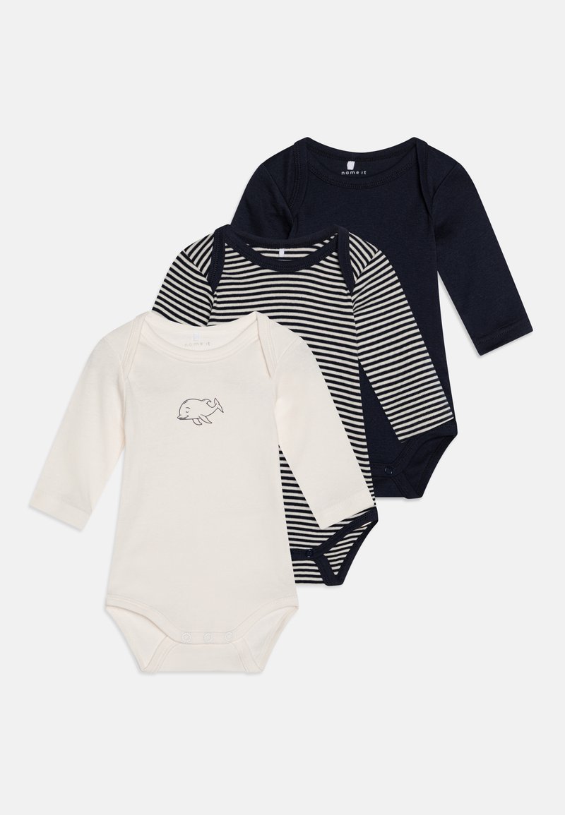 Trois bodys en jersey à manches longues pour bébé : un crème avec un motif de dauphin, un marine avec des rayures horizontales, et un uni marine. En coton doux.