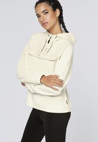 Light beige corduroy pullover with a hood, large front pocket, and drawstring closure. Features ribbed texture and relaxed fit.