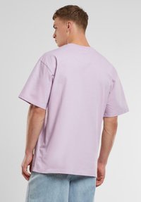 Light purple cotton t-shirt with short sleeves, relaxed fit, and reinforced stitching at the back. No graphics or patterns present.