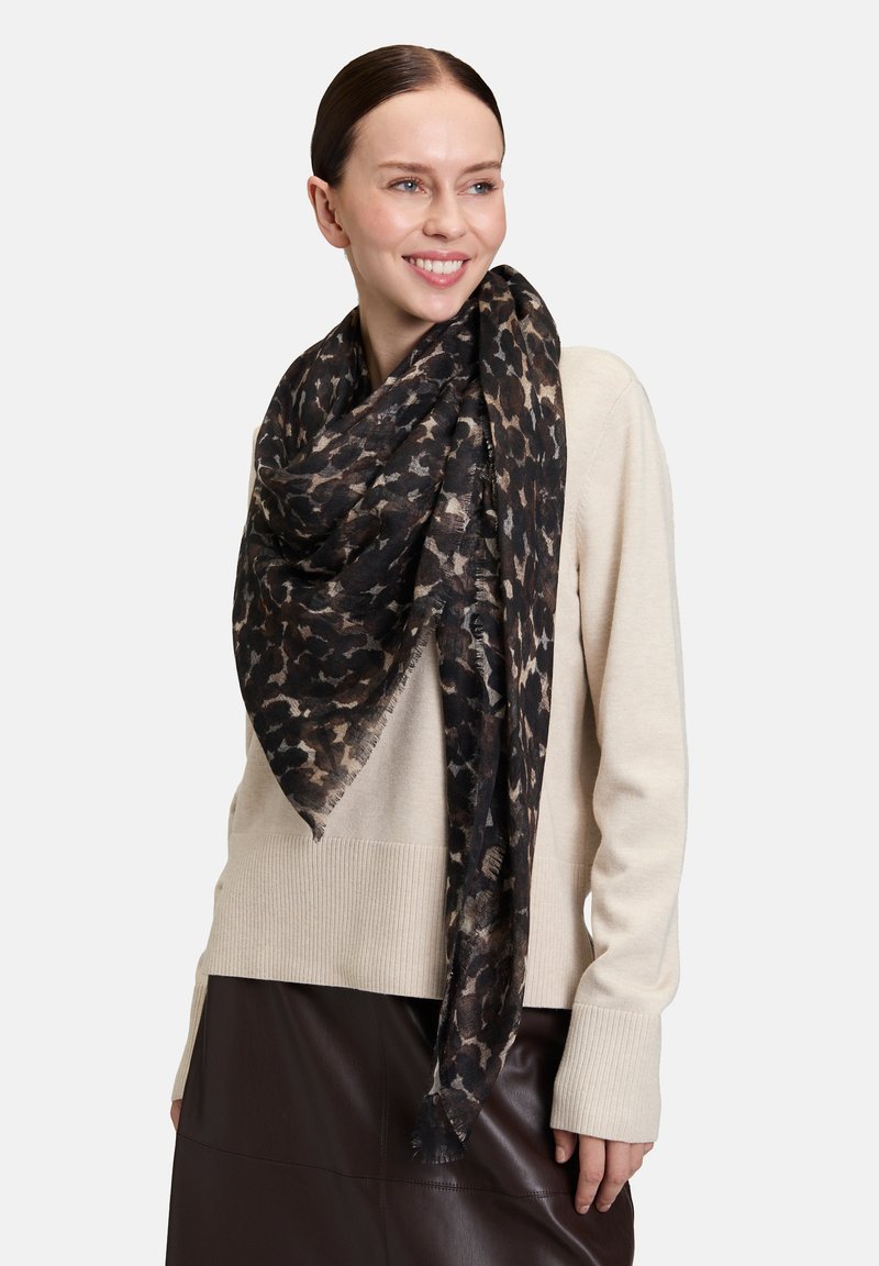 Schwarz-beige Leopardenmuster-Schal aus weichem, leichtem Stoff; mit fransigen Kanten und locker um den Hals drapiert.