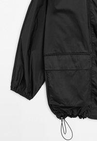 Czarny lekki rękaw kurtki z elastycznym mankietem, dużą kieszenią z patką i regulowanym ściągaczem u dołu na białym tle.