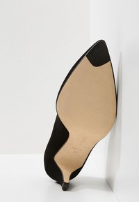 Chaussure à talon haut en daim noir avec bout pointu et semelle beige. Présente un design élégant et une base de talon stable pour un meilleur soutien.