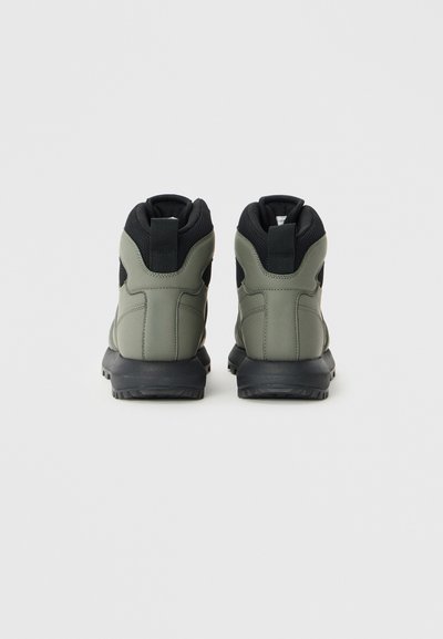 Green and black high-top sneakers with smooth rubber sole, textured fabric accents, and rear pull tabs. Features padded collars for comfort.