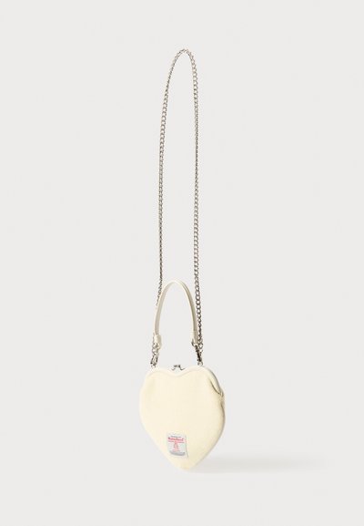 Taštička v tvare srdca z krémovej tkaniny s textúrovaným povrchom. Reťaz a horná rúčka vo farbe striebra, na prednej strane malá štítok s logom.