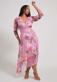 Kukkakuosisessa vaatteessa on läpinäkyvää vaaleanpunaista kangasta, jossa on kolme neljännesosaa hihat ja epäsymmetrinen helma. Vaatteessa on värikkäitä kukkakuoseja ja syvä V-pääntie.