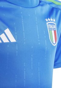 Mėlyna sportinė marškinė, pagaminta iš lygaus poliesterio, su apykakle, balta Adidas logotipu ir Italijos nacionalinės komandos ženkle, kuriame yra žvaigždžių ir juostelių.