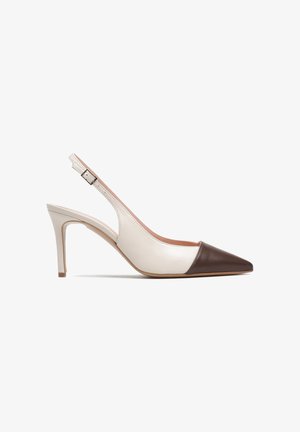 Beżowy szpilek na obcasie typu slingback z zaostrzonym ciemnobrązowym noskiem i regulowanym paskiem z klamrą.